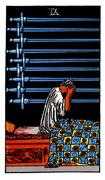 nine of swords tarot card meaning A person sits up in bed, their head in their hands, surrounded by nine swords hanging on the wall. The image conveys a sense of anxiety, worry, and despair, symbolizing mental anguish and overwhelming stress.