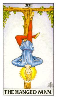 The Hanged Man tarot card from the Rider-Waite-Smith deck. A figure suspended by one foot from a tree, forming a triangle with the other leg. Symbolizing surrender, sacrifice, and a different perspective, the card conveys a sense of calm introspection and spiritual growth.